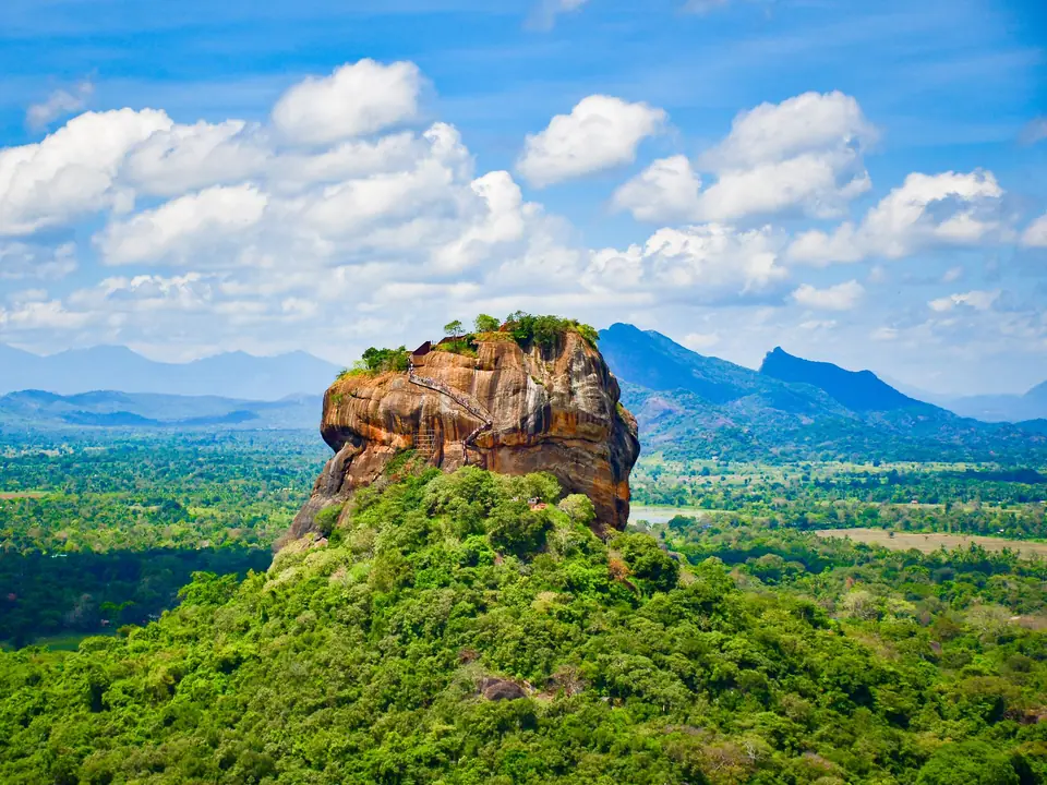 Sigiriya Lion Rock rising from the green plains under a blue sky